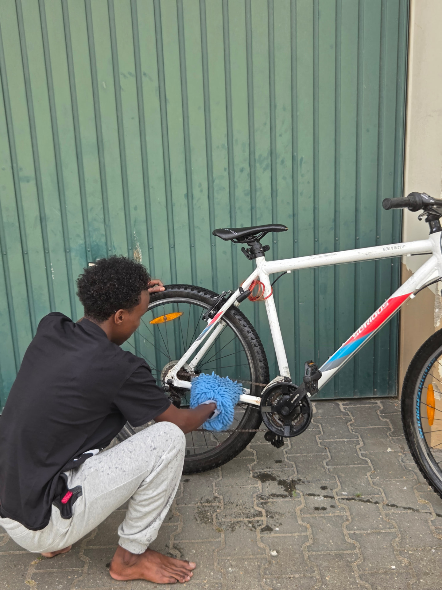 Ein junger Mann reinigt und pflegt ein Fahrrad im Werkbereich